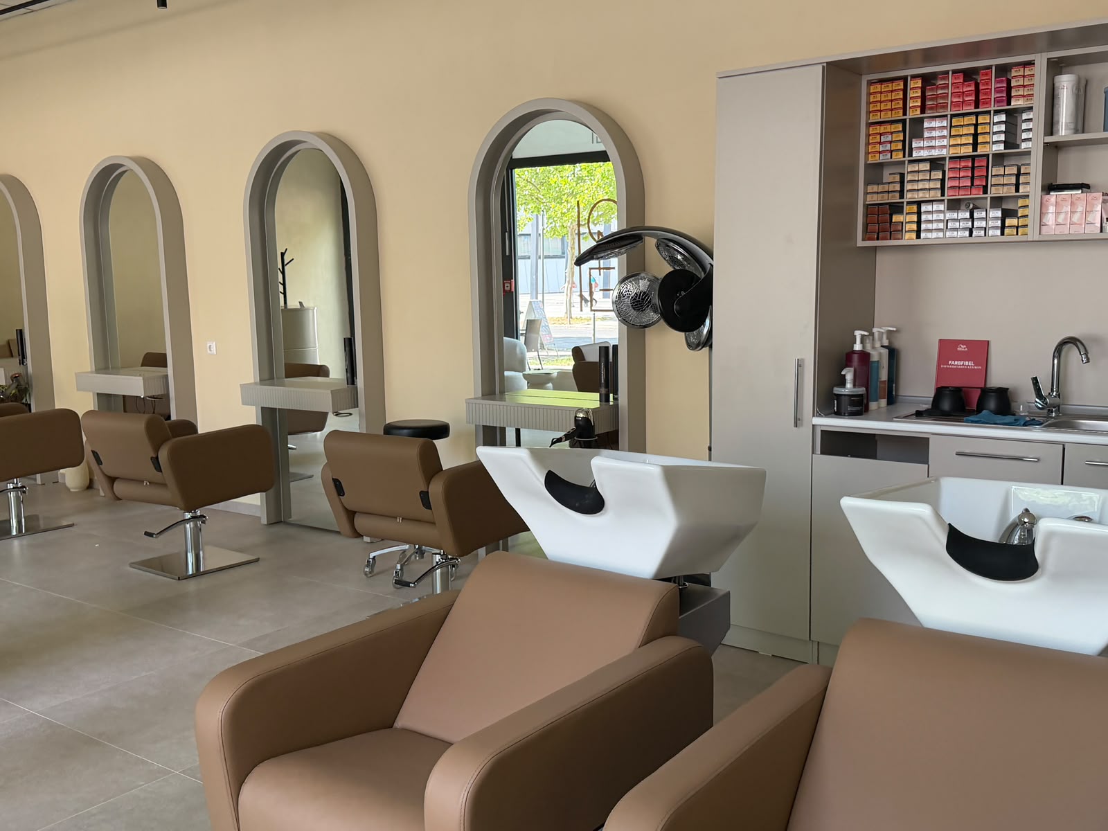 Waschplätze mit weißen Waschbecken und Regal mit Haarfarben